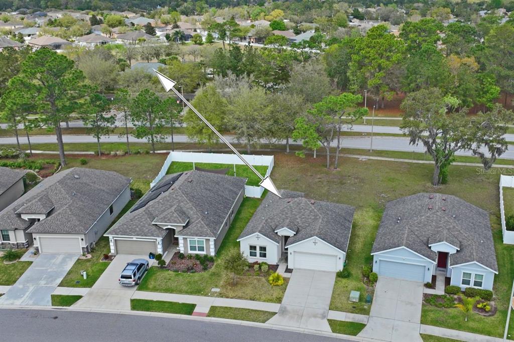 An aerial view shows a suburban street with three single-family houses and a white fence — 571 OLD WINDSOR WAY, SPRING HILL, FL