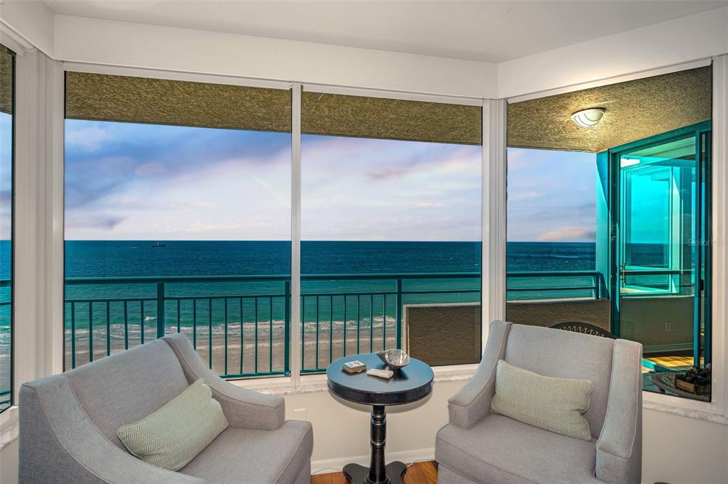 An elevated view from a balcony overlooking a sandy beach and the ocean at sunset — 1520 GULF BOULEVARD UNIT 1101, CLEARWATER BEACH, FL