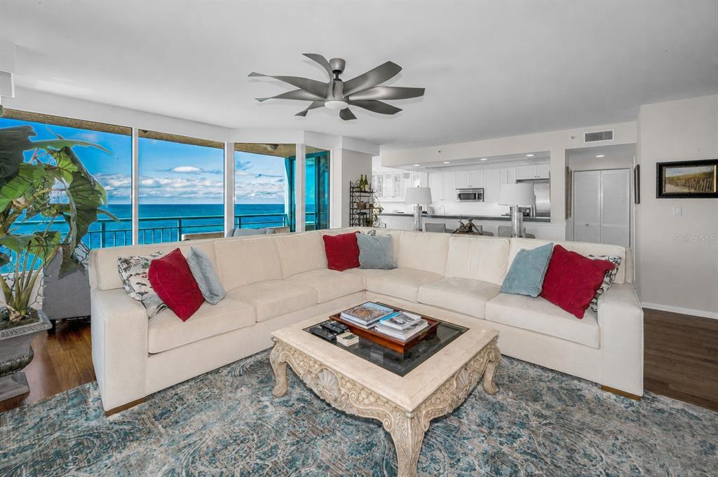 A tall, multi-story residential building with curved balconies stands behind a low wall and palm trees — 1520 GULF BOULEVARD UNIT 1101, CLEARWATER BEACH, FL
