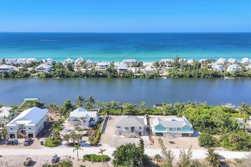 An aerial view shows houses along a waterway with the ocean in the background — 271 BOCILLA DRIVE, PLACIDA, FL