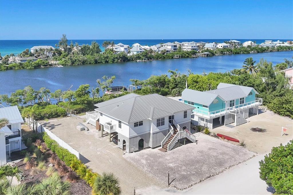 An aerial view shows two elevated houses near a waterway with the ocean beyond — 271 BOCILLA DRIVE, PLACIDA, FL