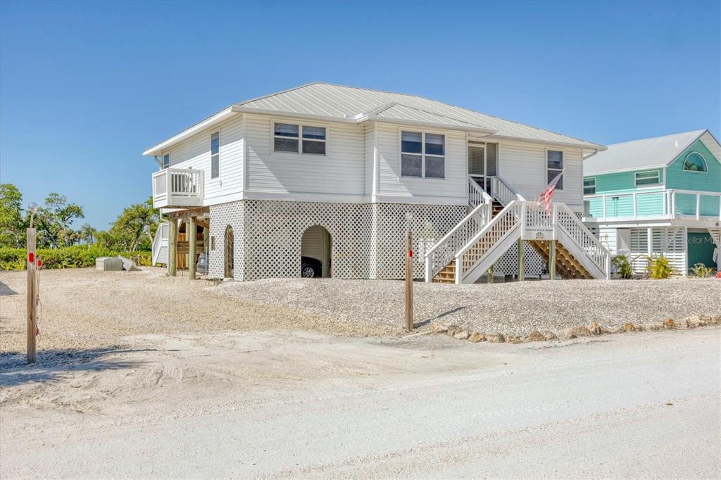 A white elevated house with a lattice-enclosed ground level and stairs leading to the entrance — 271 BOCILLA DRIVE, PLACIDA, FL