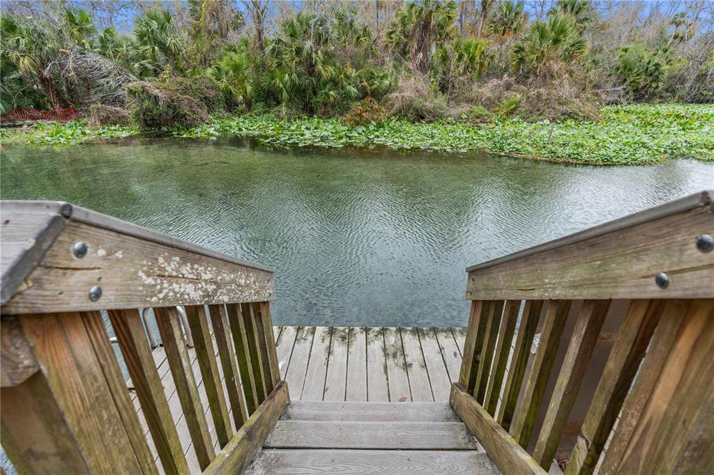 A wooden staircase leads down to a dock overlooking a clear, vegetation-lined waterway — 26 E KELLY PARK ROAD, APOPKA, FL