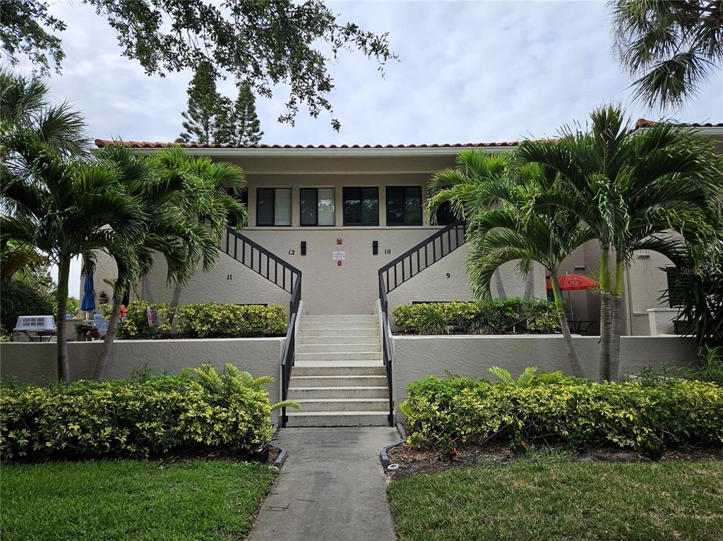 A paved driveway leads toward a gated entrance featuring an American flag and landscaping — 1800 MARINER DRIVE UNIT 9, TARPON SPRINGS, FL