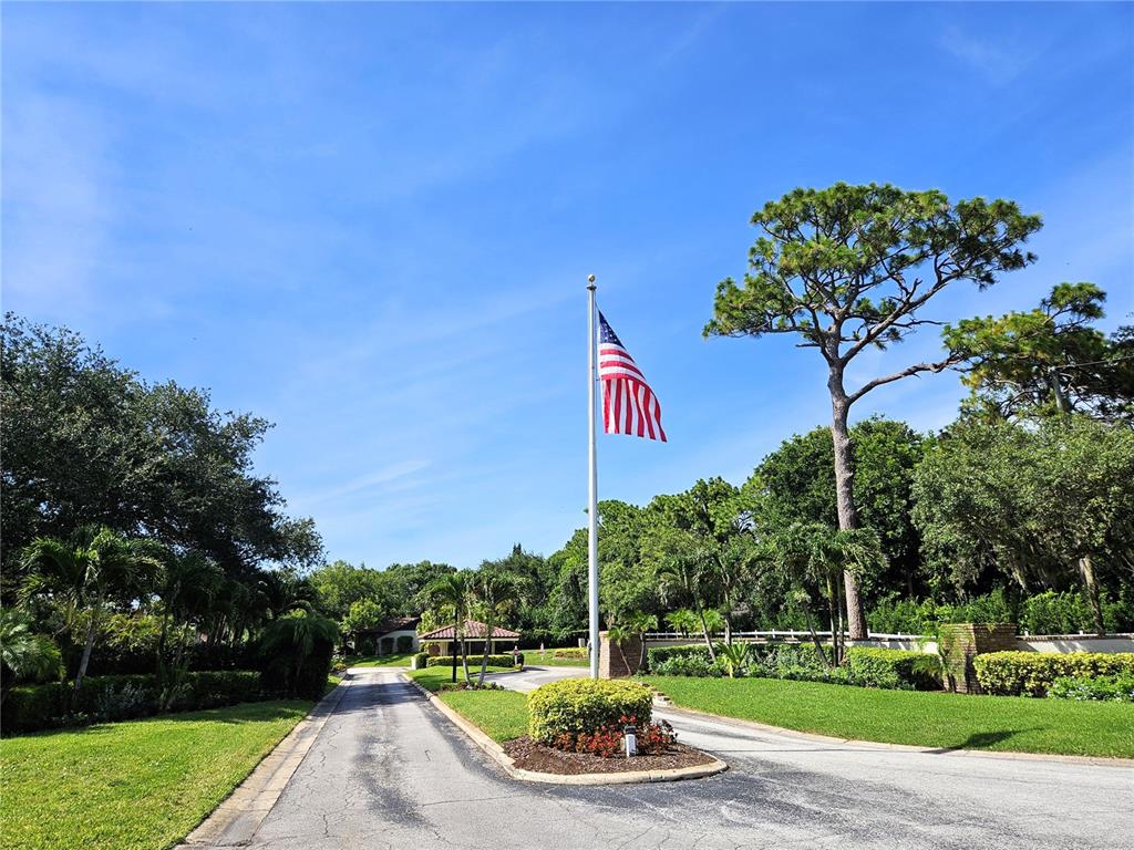 A two-story apartment building exterior features a central staircase, palm trees, and landscaped bushes — 1800 MARINER DRIVE UNIT 9, TARPON SPRINGS, FL