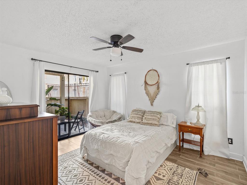A bedroom with a bed, ceiling fan, sliding glass door, and wood-look tile flooring — 8653 MALLARD RESERVE DRIVE UNIT 103, TAMPA, FL