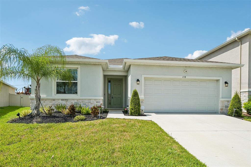 A single-story house with a light-colored stucco exterior, stone accents, and a two-car garage — 178 MANGROVE MANOR DRIVE, APOLLO BEACH, FL