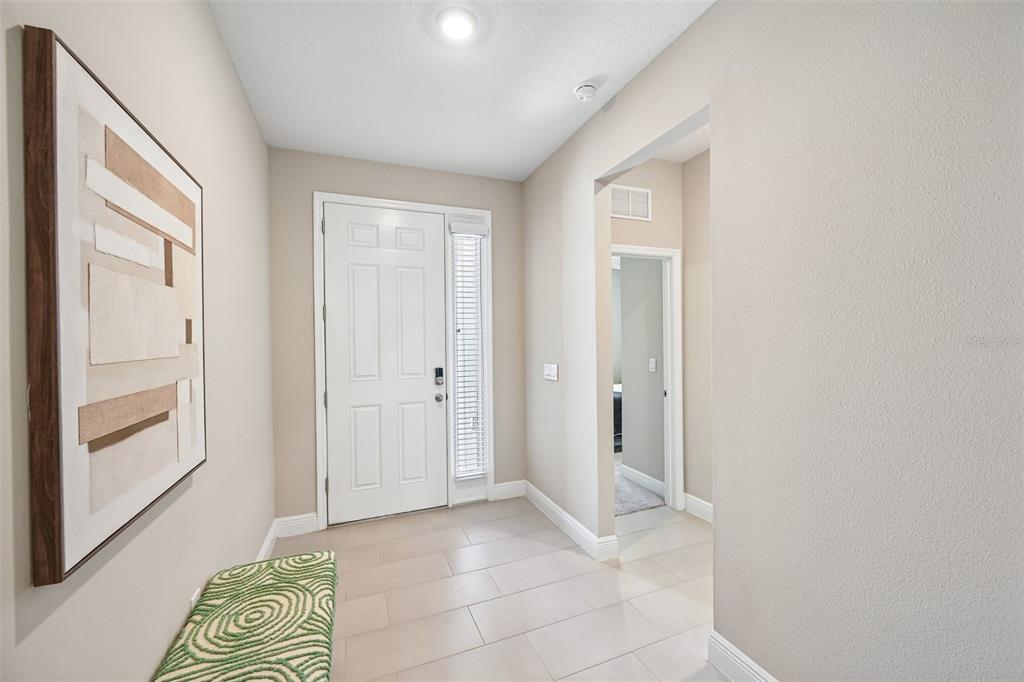 An entryway features light tile flooring, a white front door, and a textured wall art piece — 178 MANGROVE MANOR DRIVE, APOLLO BEACH, FL