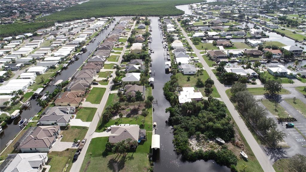 An aerial view shows a residential canal neighborhood with houses, boat docks, and surrounding vegetation — 4114 PALM DRIVE, PUNTA GORDA, FL