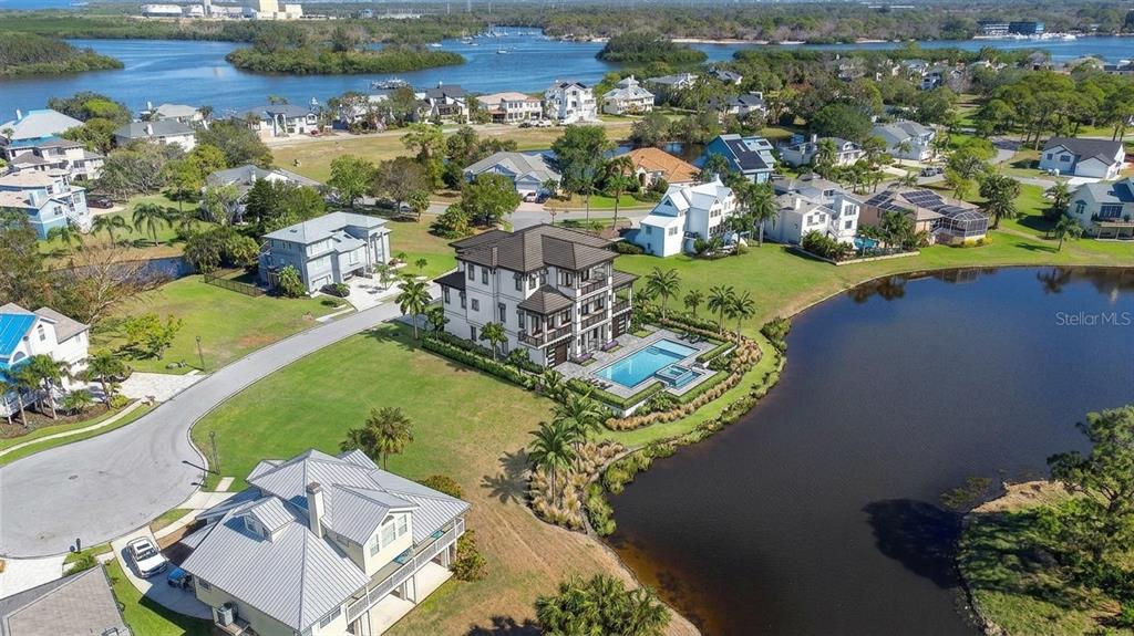 An aerial view shows a multi-story house with a pool beside a lake in Florida — 85 SANDPIPER POINTE, TARPON SPRINGS, FL