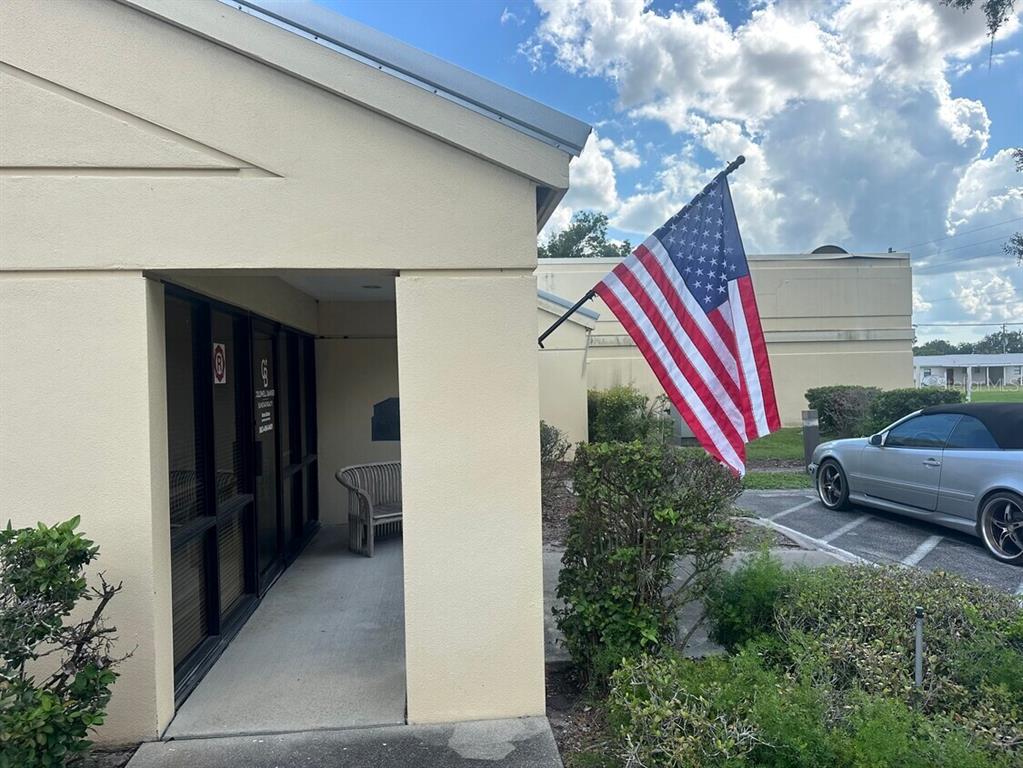 An exterior view of a building entrance with a bench, an American flag, and a car — 920 N MILLS AVENUE, ARCADIA, FL