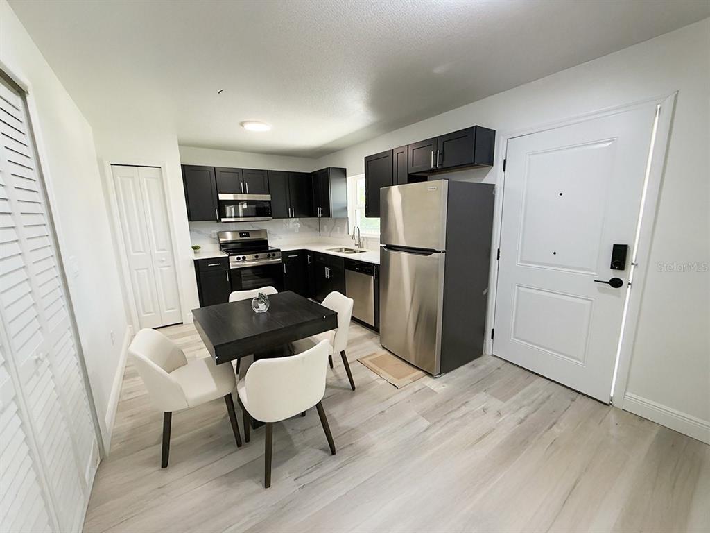 A kitchen features dark cabinets, stainless steel appliances, white countertops, and light wood-look flooring — 2201 CONWAY DRIVE UNIT 102, DELTONA, FL