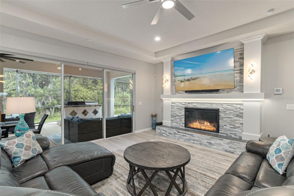 A living room features a stone fireplace, a wall-mounted television, and sliding glass patio doors — 5512 74TH PLACE E, ELLENTON, FL