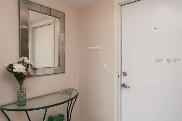 An entryway features a glass console table, a decorative mirror, and a white front door — 7153 W COUNTRY CLUB DRIVE N UNIT 146, SARASOTA, FL