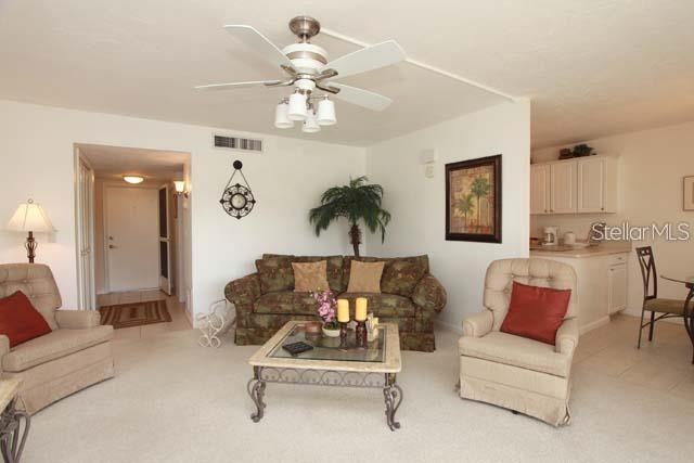 A living room features a patterned sofa, two armchairs, a coffee table, and a ceiling fan — 7153 W COUNTRY CLUB DRIVE N UNIT 146, SARASOTA, FL