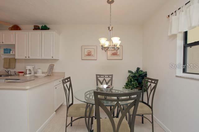 A dining area with a glass table, four chairs, and a chandelier next to a kitchen — 7153 W COUNTRY CLUB DRIVE N UNIT 146, SARASOTA, FL