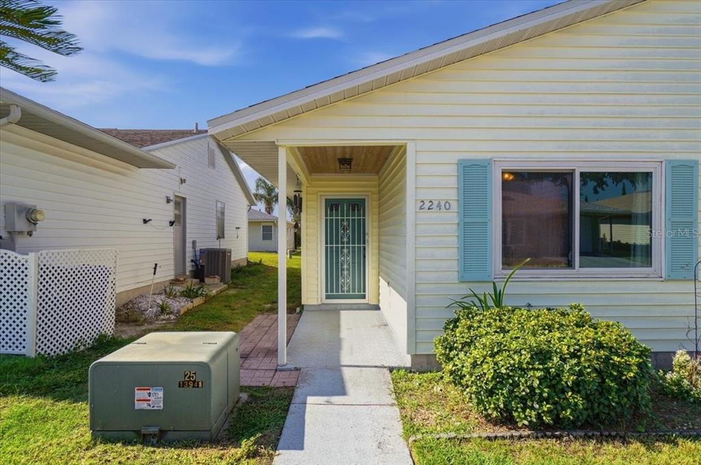 A light yellow house exterior features a front entrance, blue shutters, and a green utility box — 2240 SEA ISLAND CIRCLE N, LAKELAND, FL
