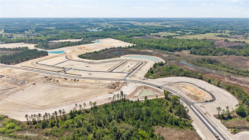 An aerial view shows a large residential construction site with paved roads and retention ponds — 674 FLORIDA FERN AVENUE, HOWEY IN THE HILLS, FL