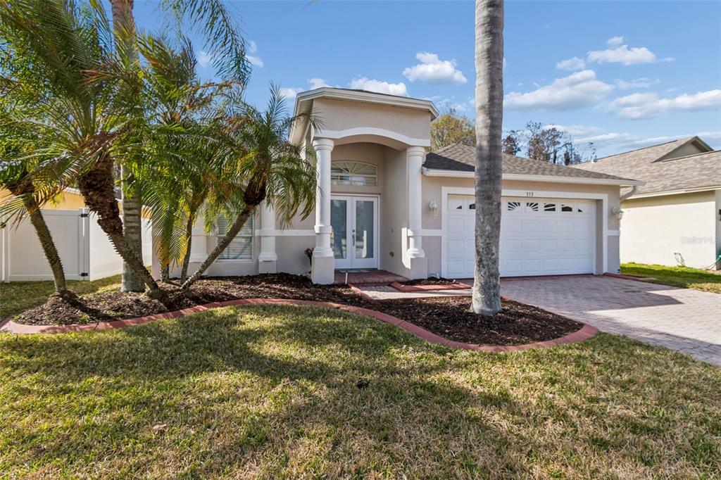 A single-story house with a beige stucco exterior, a two-car garage, and palm trees — 353 BAY ARBOR BOULEVARD, OLDSMAR, FL