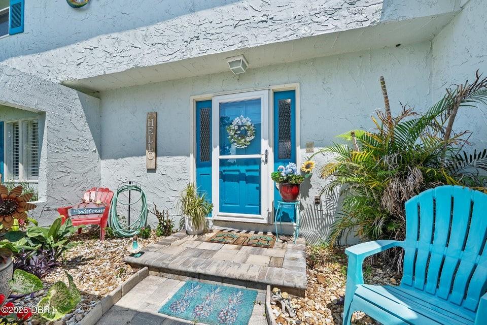 The exterior of a house features a blue front door, a stone patio, and chairs — 461 ANDREWS STREET, ORMOND BEACH, FL