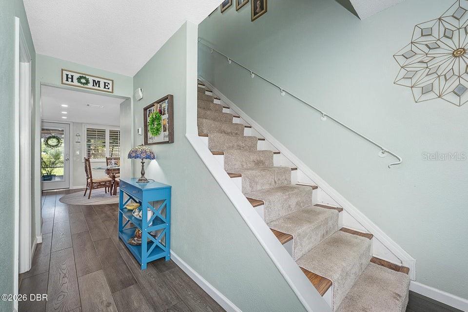 A staircase with carpeted steps sits next to a blue console table in a hallway — 461 ANDREWS STREET, ORMOND BEACH, FL