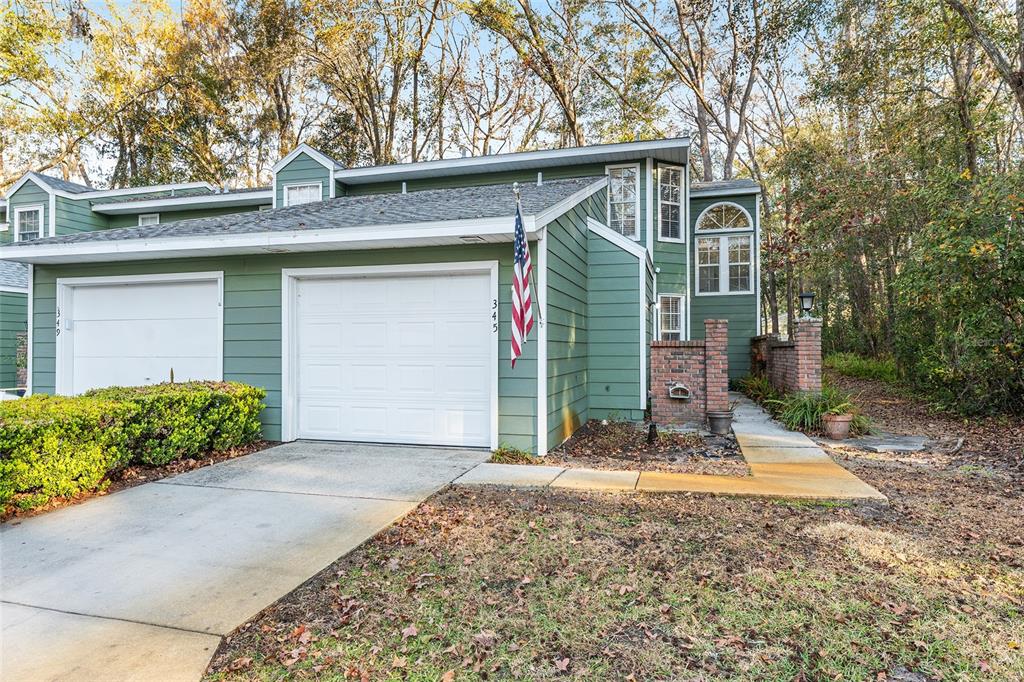 A green-sided townhouse with a white garage door, brick accents, and a front walkway — 345 NW 48TH BOULEVARD UNIT K, GAINESVILLE, FL