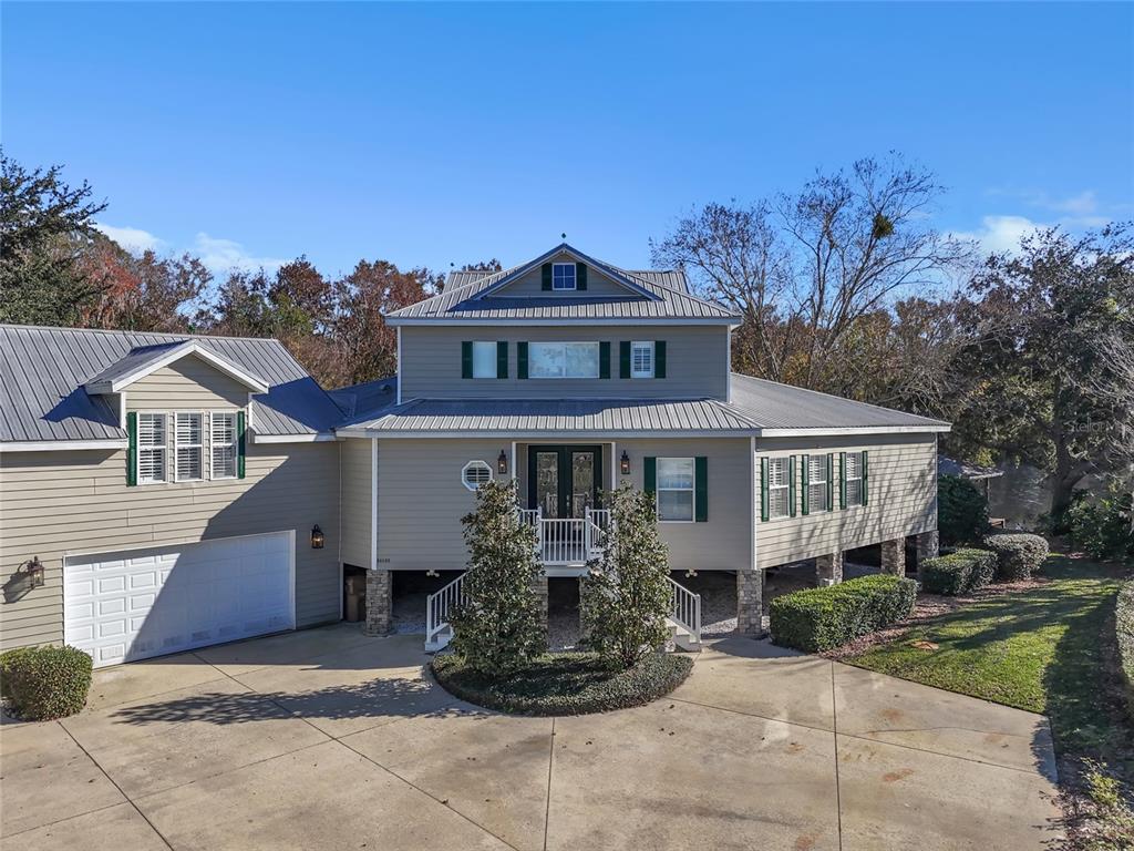 A two-story house with light siding, a metal roof, and an elevated front entrance — 56633 OTTER ROAD, ASTOR, FL