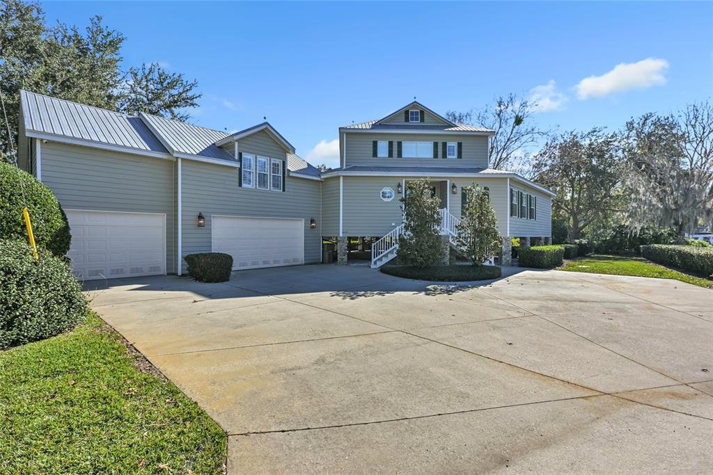 A two-story house with light green siding, a metal roof, and a large concrete driveway — 56633 OTTER ROAD, ASTOR, FL