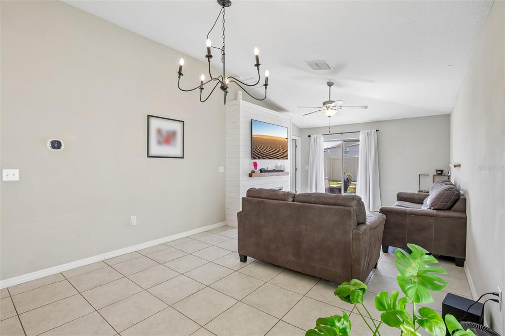 A living room features tile flooring, a chandelier, a ceiling fan, and a mounted television — 9415 LEMON DROP LOOP, SUN CITY CENTER, FL