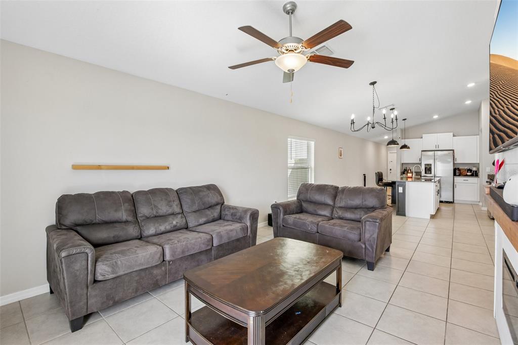 A living room with gray sofas, a coffee table, and an open kitchen beyond — 9415 LEMON DROP LOOP, SUN CITY CENTER, FL