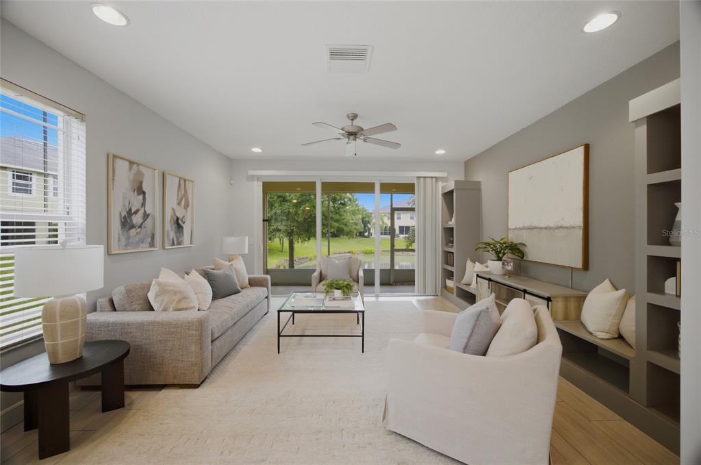 A living room with a large television, built-in shelving, a wood coffee table, and sliding doors — 485 HARBOR RIDGE DRIVE, PALM HARBOR, FL