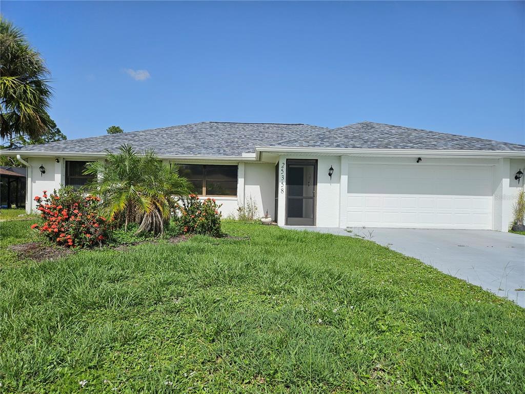 A single-story house with a white exterior, a two-car garage, and a front lawn — 25358 AYSEN DRIVE, PUNTA GORDA, FL