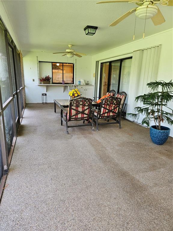 A screened-in patio features a concrete floor, ceiling fans, and a small outdoor bar area — 25358 AYSEN DRIVE, PUNTA GORDA, FL