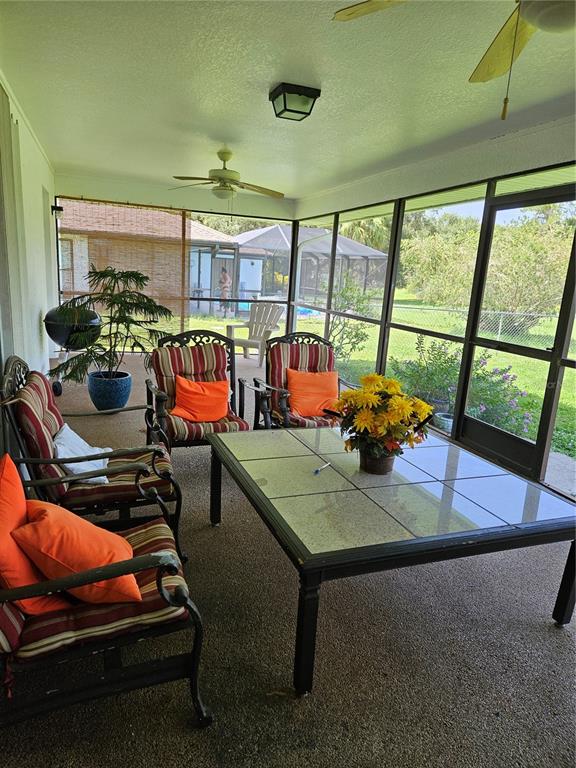 A screened-in patio features a tiled dining table, outdoor seating, and a ceiling fan — 25358 AYSEN DRIVE, PUNTA GORDA, FL