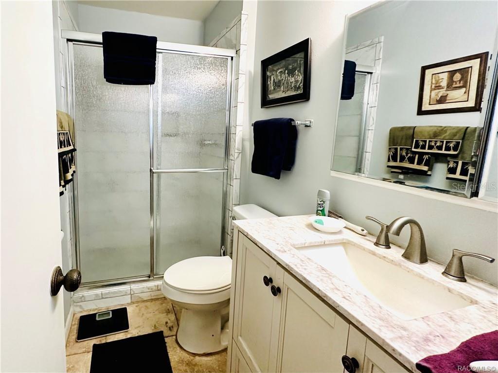 A bathroom features a walk-in shower, a toilet, and a vanity with a white sink — 2400 FOREST DRIVE UNIT 227, INVERNESS, FL
