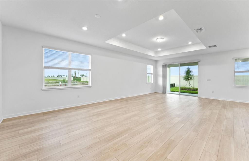 A modern kitchen features white cabinetry, a central island, stainless steel appliances, and light flooring — 16816 HARMONY RIVER LANE, PARRISH, FL