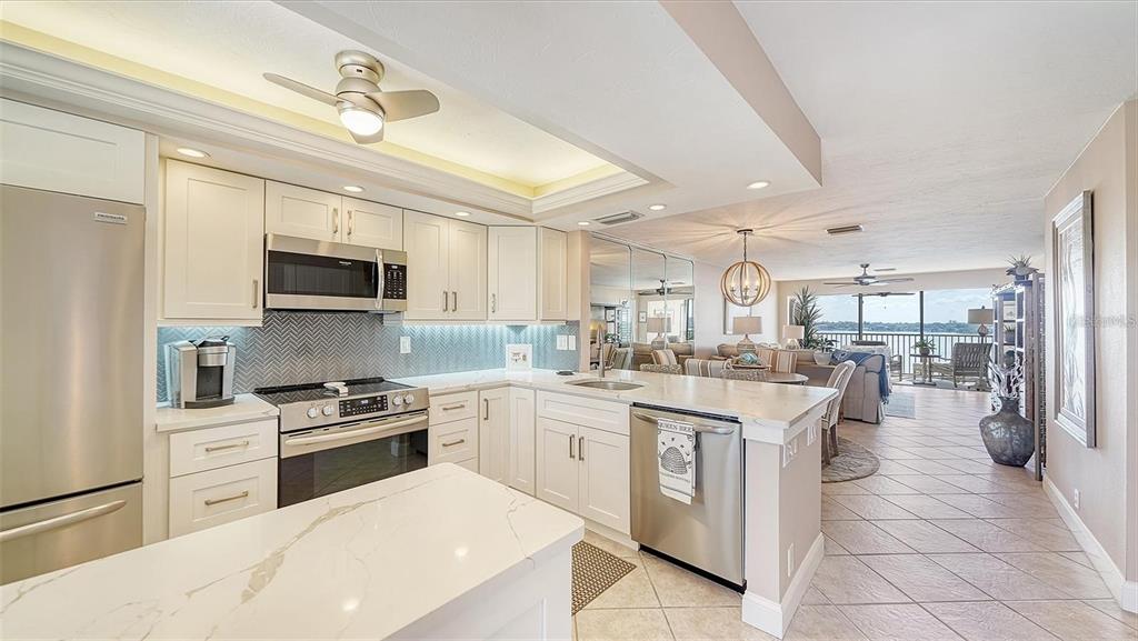 A modern kitchen with white cabinets, stainless steel appliances, and a view of the water — 8911 MIDNIGHT PASS ROAD UNIT 514, SARASOTA, FL