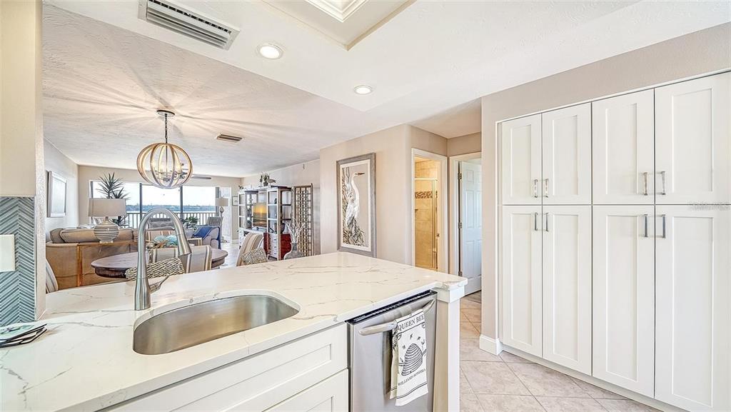 A kitchen with white cabinets and a marble-topped island overlooks a living area and balcony — 8911 MIDNIGHT PASS ROAD UNIT 514, SARASOTA, FL