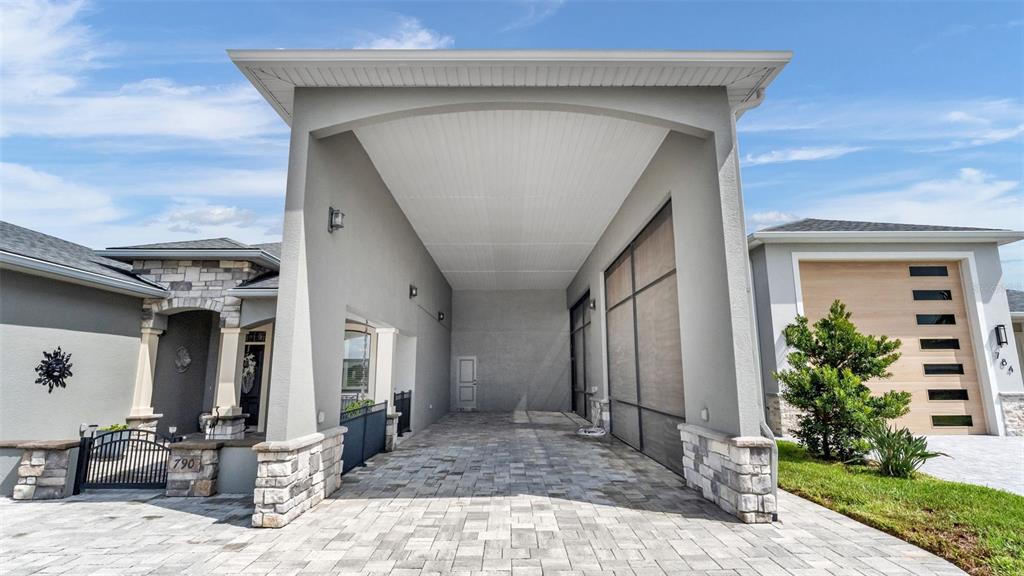 A paved driveway leads to a large covered porte-cochère attached to a modern house exterior — 790 TEABERRY TRAIL, POLK CITY, FL