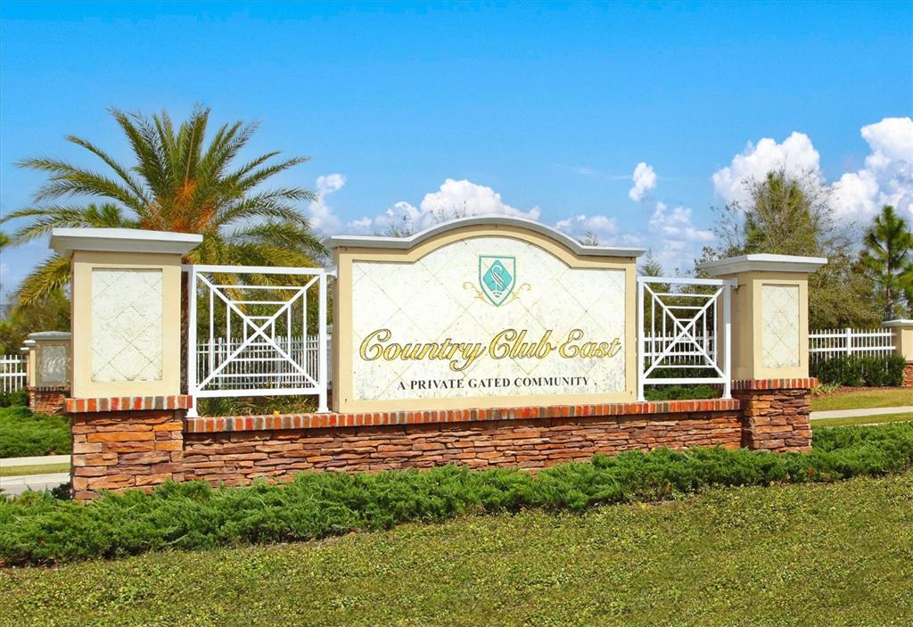 A stone and stucco monument sign for Country Club East stands in a grassy landscape — 7118 WESTHILL COURT, BRADENTON, FL