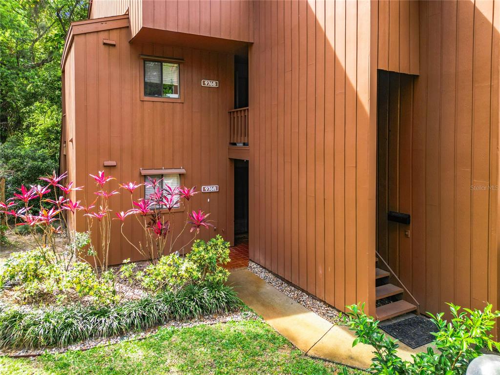 A two-story brown wood-sided building with two unit entrances and a small front garden — 976 E MICHIGAN STREET UNIT A, ORLANDO, FL