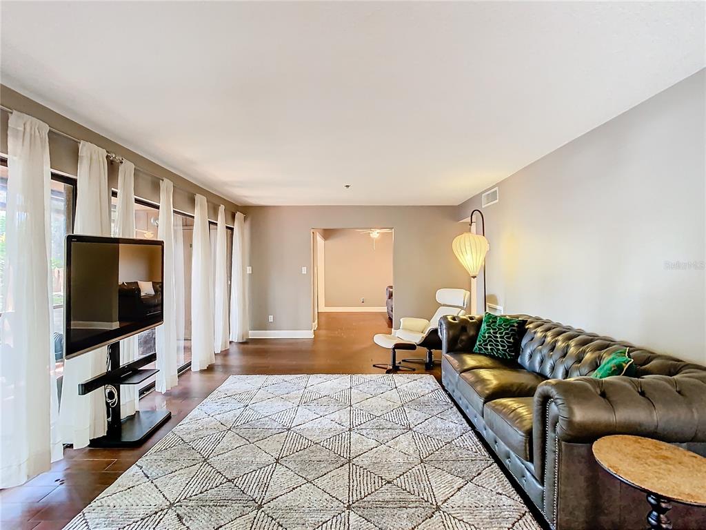 A living room features a tufted leather sofa, a geometric rug, and floor-to-ceiling curtains — 976 E MICHIGAN STREET UNIT A, ORLANDO, FL