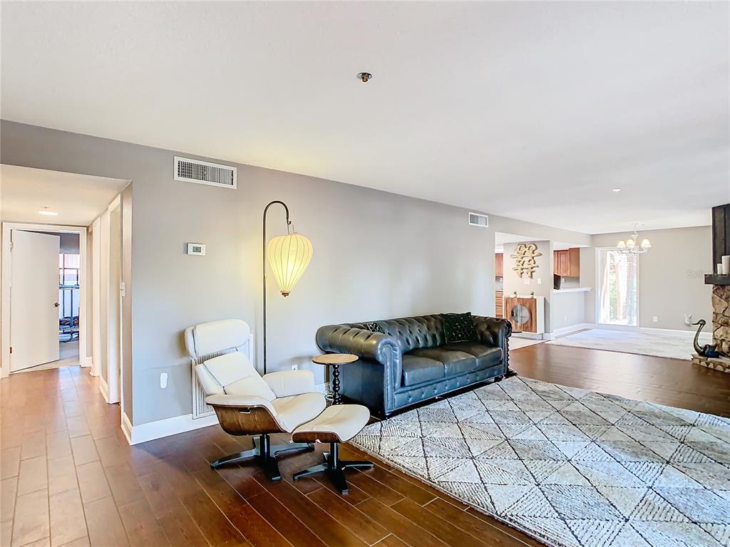 A living room features a dark leather sofa, a white lounge chair, and wood flooring — 976 E MICHIGAN STREET UNIT A, ORLANDO, FL