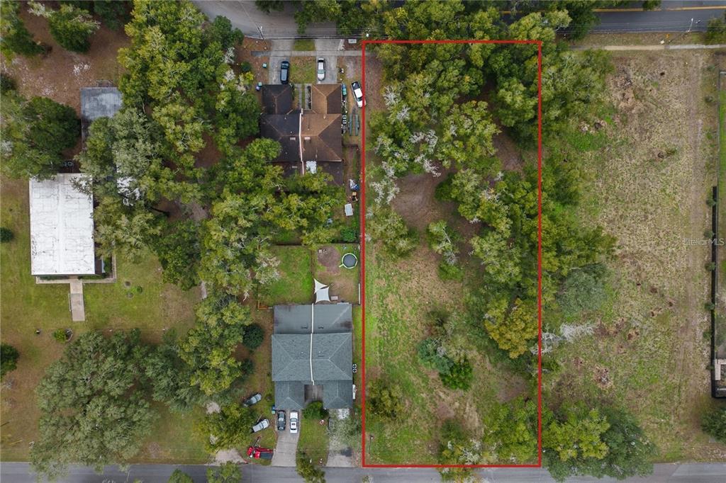 An aerial view shows a rectangular, tree-covered vacant lot outlined in red next to houses — SAND AVENUE, APOPKA, FL