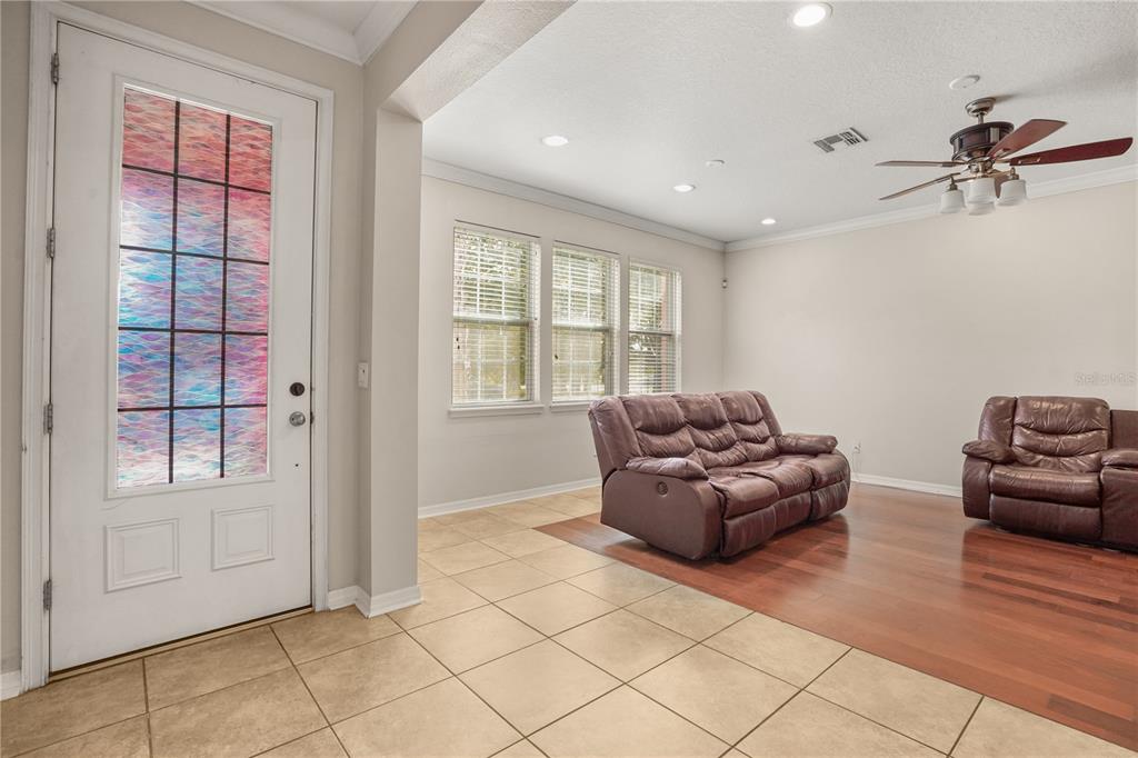 A staircase with wood-look treads and a white handrail sits beside a tiled hallway — 561 TELFAIR SQUARE COURT, SANFORD, FL