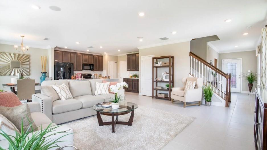 A living room with a beige sofa, coffee table, and stairs leading to an upper floor — 1465 TRINIDAD STREET, DELAND, FL