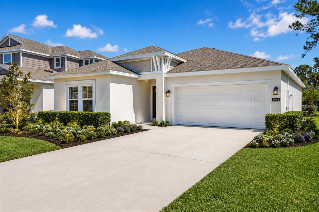 A single-story house with a white stucco exterior, a two-car garage, and landscaped front yard — 3963 WILLOWBROOK DRIVE, EDGEWATER, FL