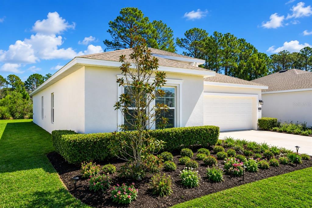 A single-story house with a white stucco exterior, a two-car garage, and landscaped front yard — 3963 WILLOWBROOK DRIVE, EDGEWATER, FL