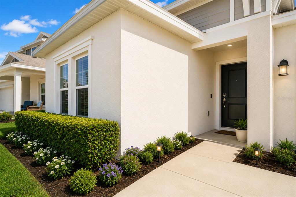 A view of a house exterior featuring a white stucco facade, dark door, and landscaping — 3963 WILLOWBROOK DRIVE, EDGEWATER, FL