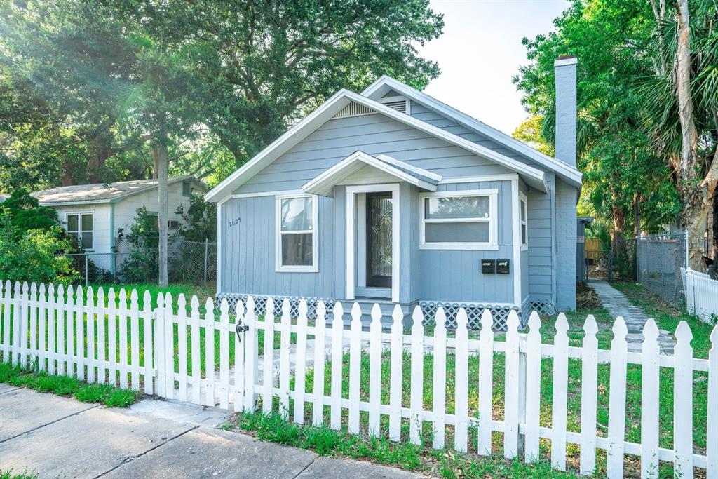 A light blue house with a white picket fence and a chimney stands outdoors — 2625 4TH AVENUE S, ST PETERSBURG, FL